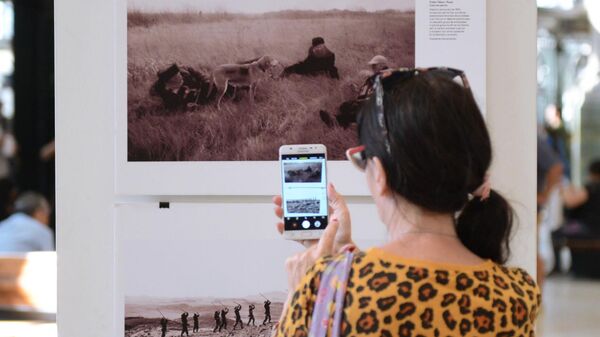 Посетительница фотографирует на мобильный телефон одну из фотографий на выставке работ победителей Международного конкурса фотожурналистики имени Андрея Стенина